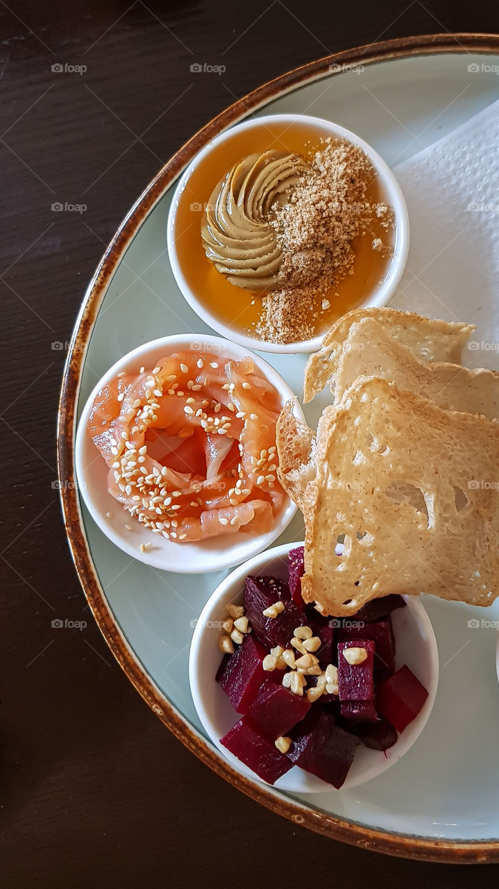 On the plate different types of healthy snacks like humus, salted salmon fish and red beet with nuts.