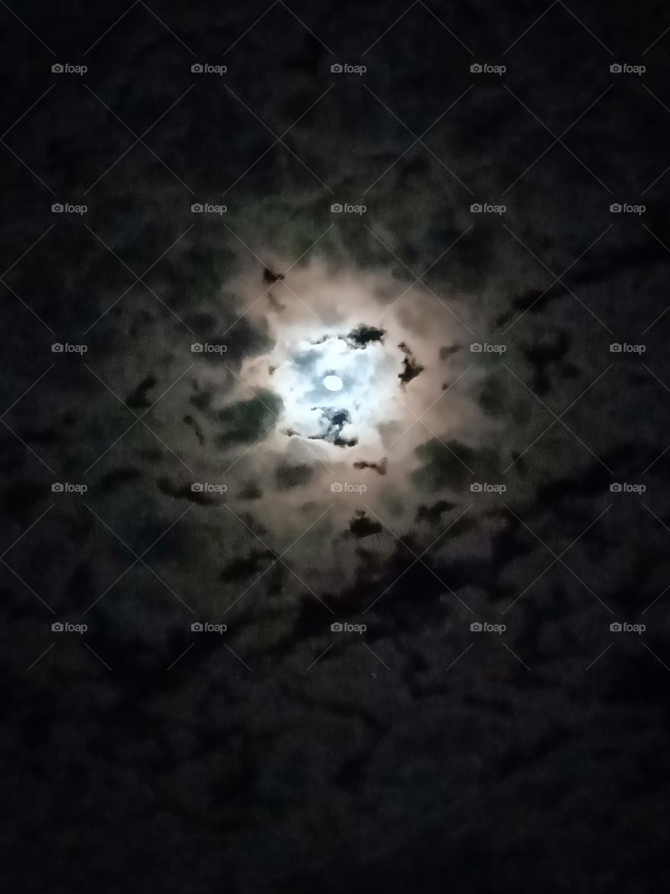 Between the clouds a beautiful moon rises in the night sky