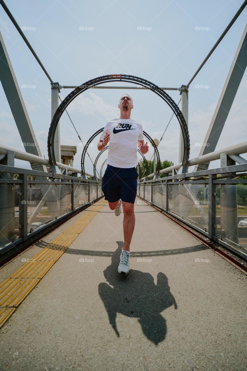 Young man running over a pedestrian bridge