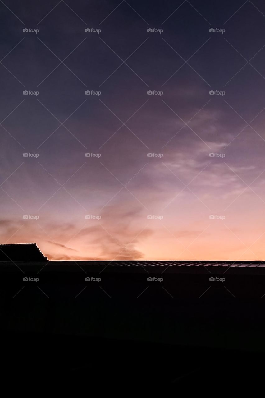 The sun rises from behind the roof of the house in low angle view