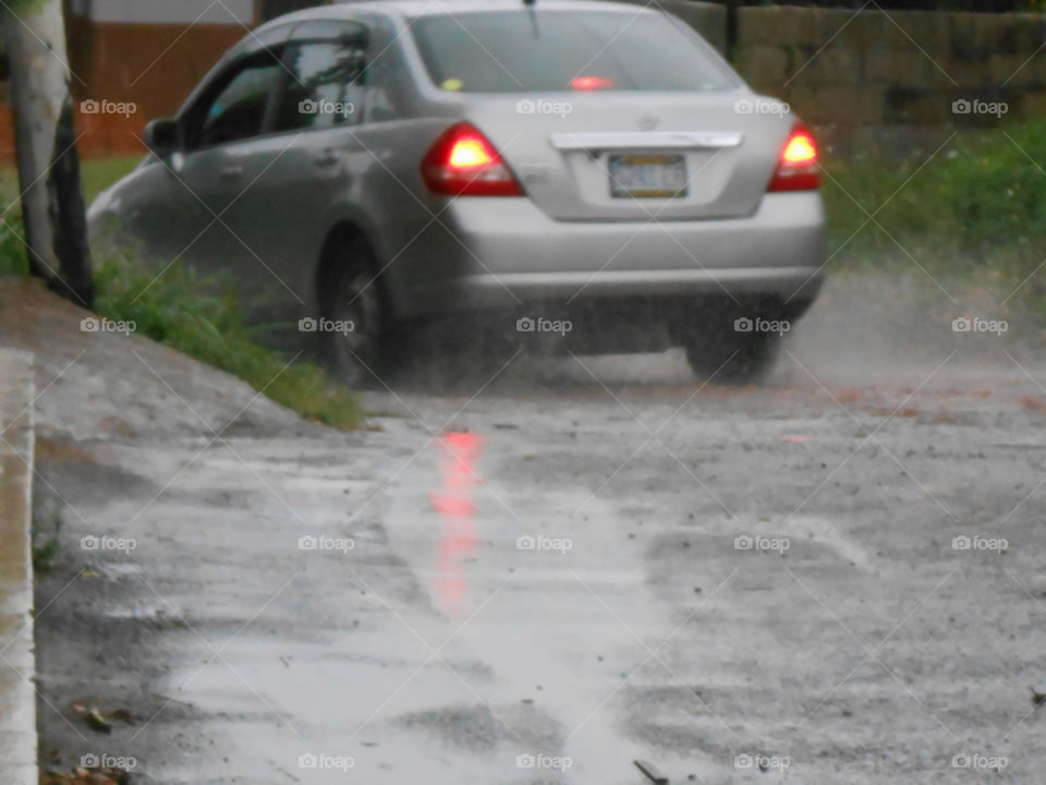 Car Traversing The Wet Road In The Rain With Lights On