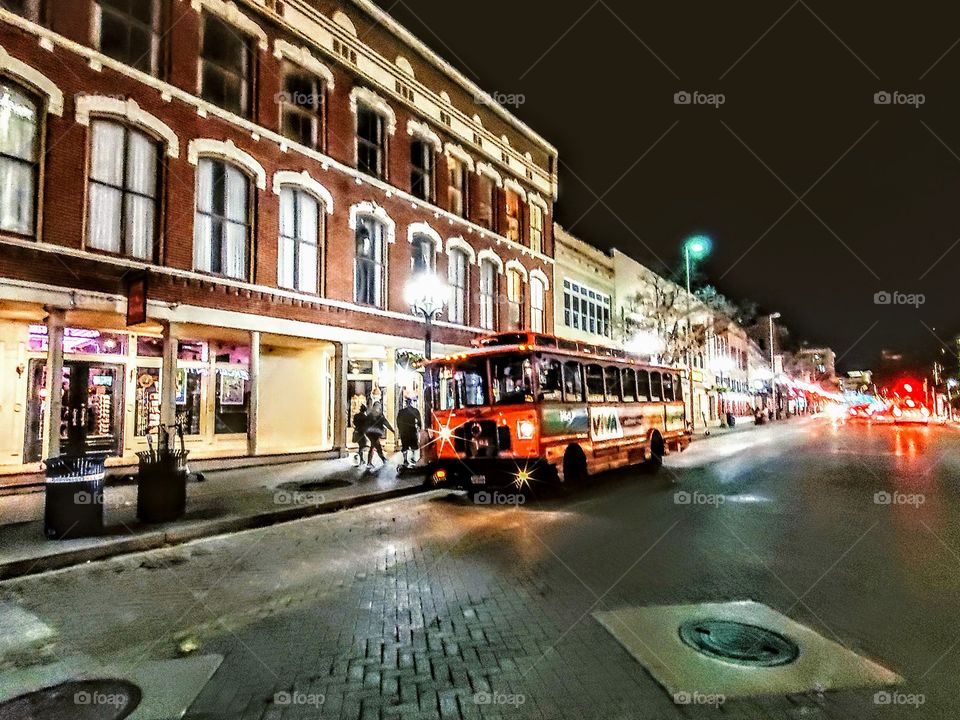 Downtown old San Antonio TX . Trolly on am old brick road in front of an old brick building at night.