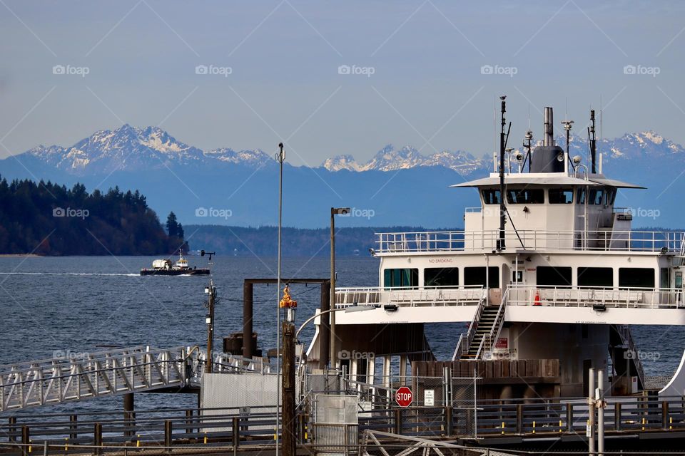 A ferry docks to collect commuters to Anderson Island near Steilacoom, Washington on a clear December afternoon. Olympic Mountains show snow capped tops in background