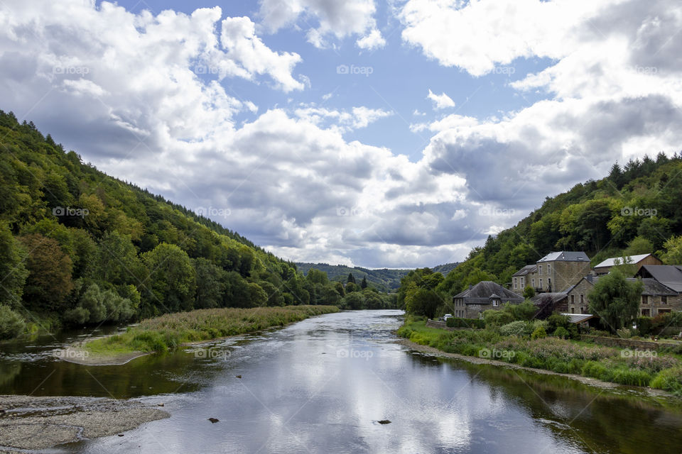 A landscape photograph of a river in the belgian ardennes in la fayette. there is a nice reflection of the clouds in the water.