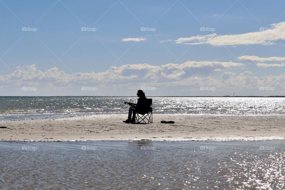 Singing to the wind. Lone guitarist musician surrounded by ocean 