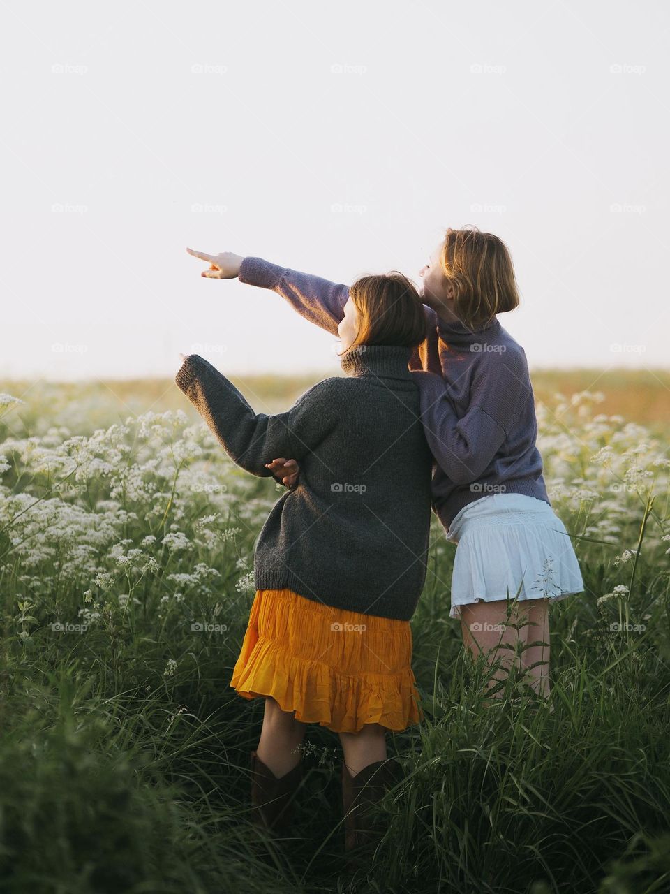 Two young beautiful woman’s standing in field in sunny summer day, portrait of woman