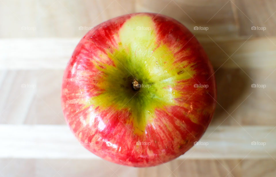 Elevated view of one beautiful crisp fresh red apple with green and yellow colors isolated on wood table healthy choices art photography background