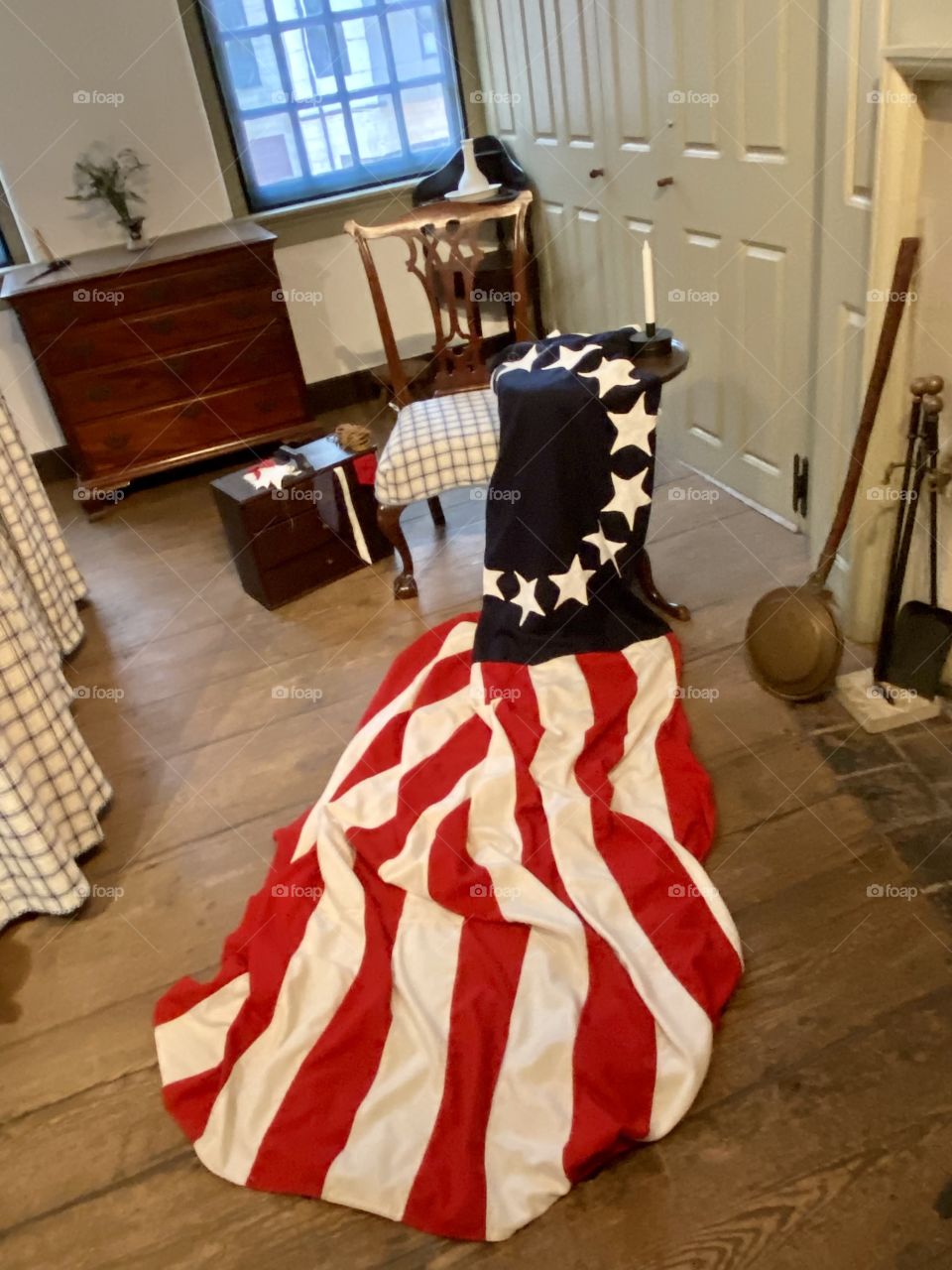 A replica of the first American flag with 13 stars lying on a chair in an old-fashioned bedroom