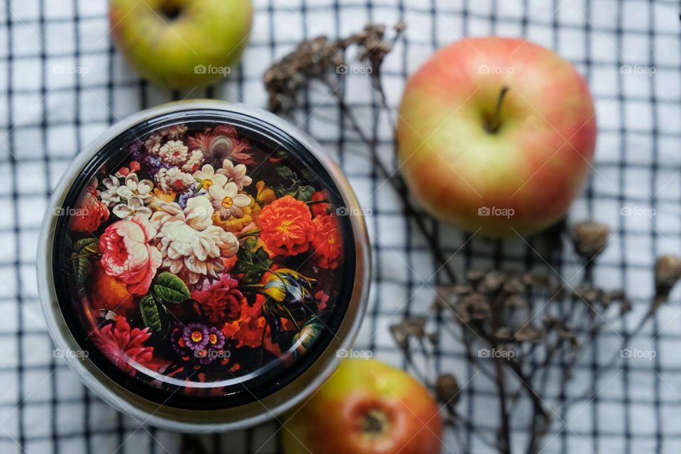 Lid of a jar with pickled vegetables close-up with a checkered napkin and apples on the background