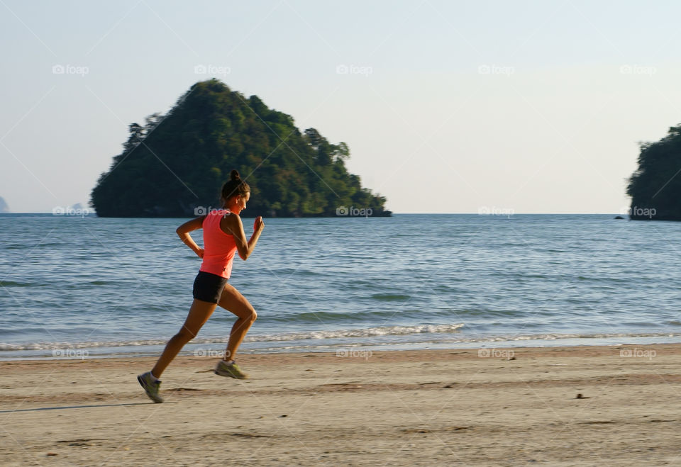 Young woman running on sandy beach