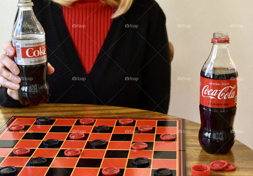 Woman playing checkers and drinking Diet Coke 