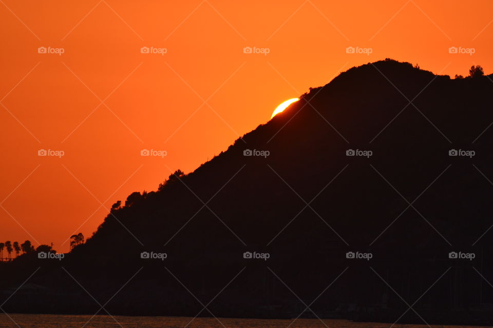 Silhouette of mountain against orange sky