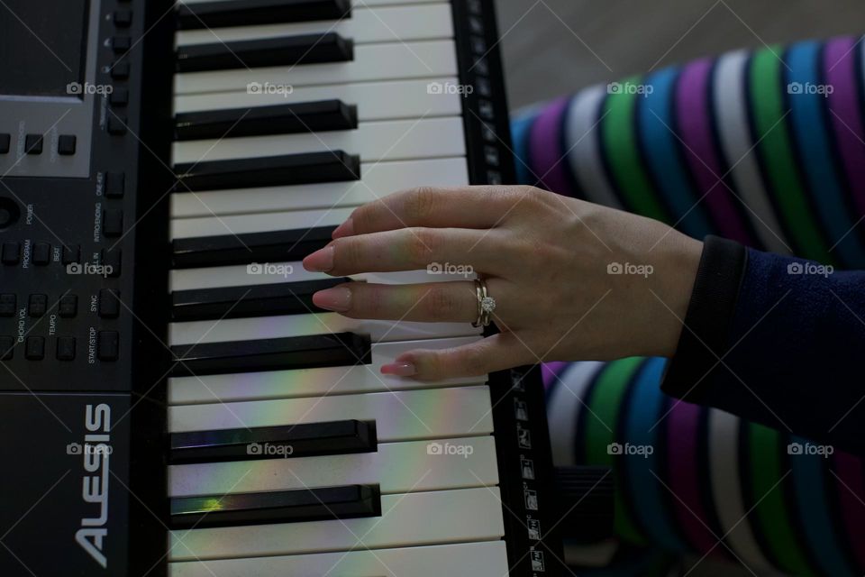 Playing the Rainbow; Woman playing keyboard with rainbow light across keys