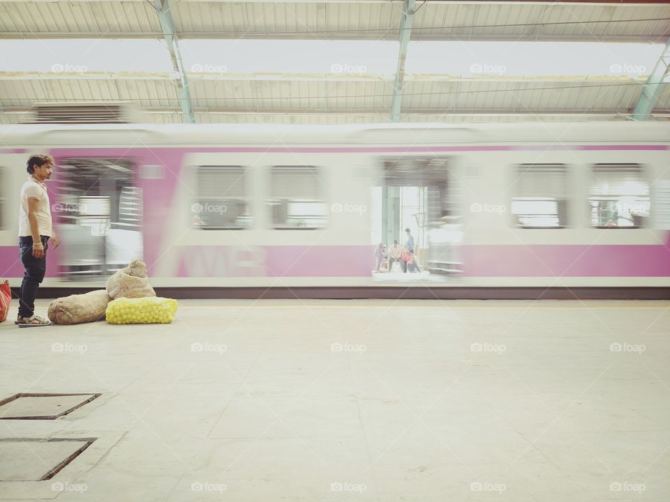 man is standing as train moves with his vegi bags