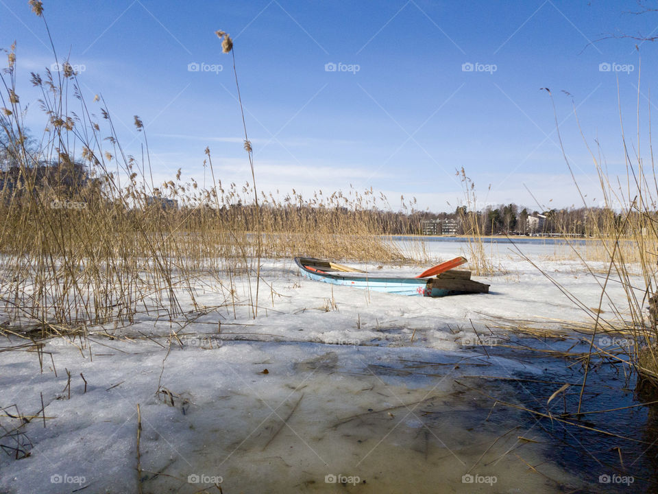 Abandoned rowing boat full of ice and snow in the middle of reeds and ice by the Baltic Sea in Espoo, Finland