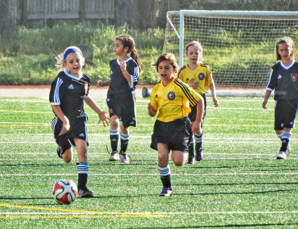 Love Running. Young Girls Running Across Soccer Pitch