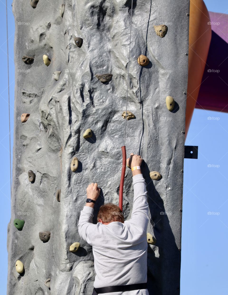 Man attempting to climb outdoor rock climbing tower