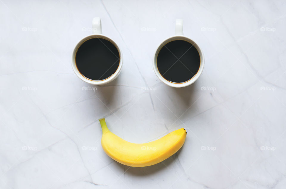 Business working morning with cup of hot coffee, sweet yellow banana on white background close up. Top view, copy space, flat lay, mockup. happy smile