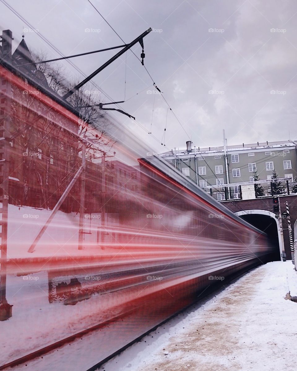 Commuting train is arriving at an open air train station, at a slow shutter speed 