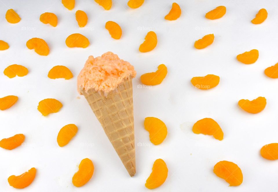 Orange sherbet on a waffle cone with mandarin oranges surrounding the cone