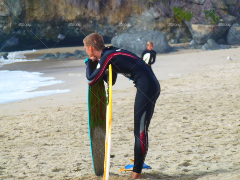 A surfer waits on the beach for bigger waves in Laguna Beach, California