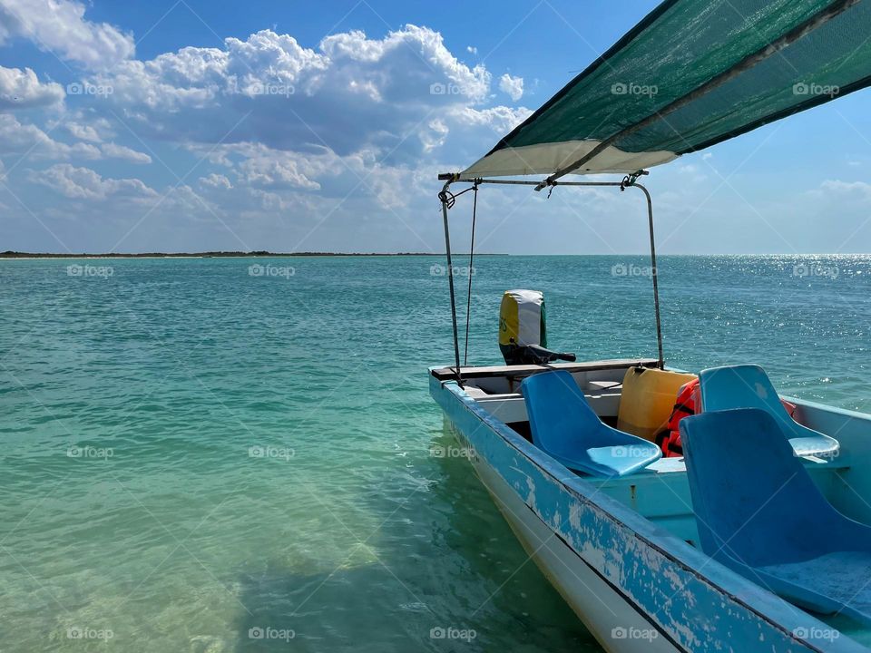 Blue-white boat moored on the beach by the azure sea near the town of Rio Lagartos, Yucatan, Mexico. Peaceful vacation in the Caribbean.