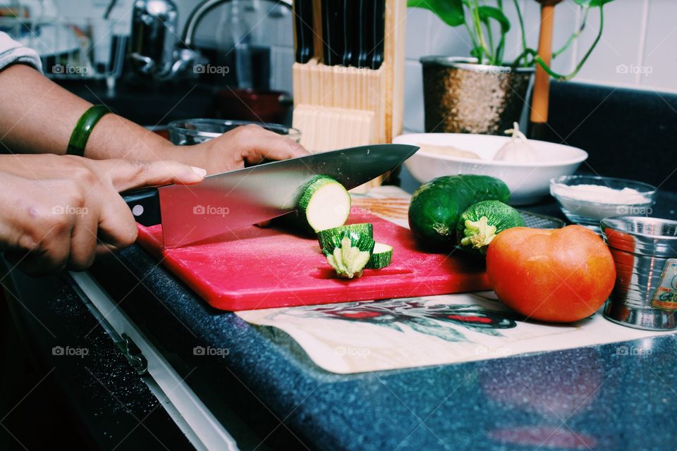 Young woman working in kitchen cutting zucchini