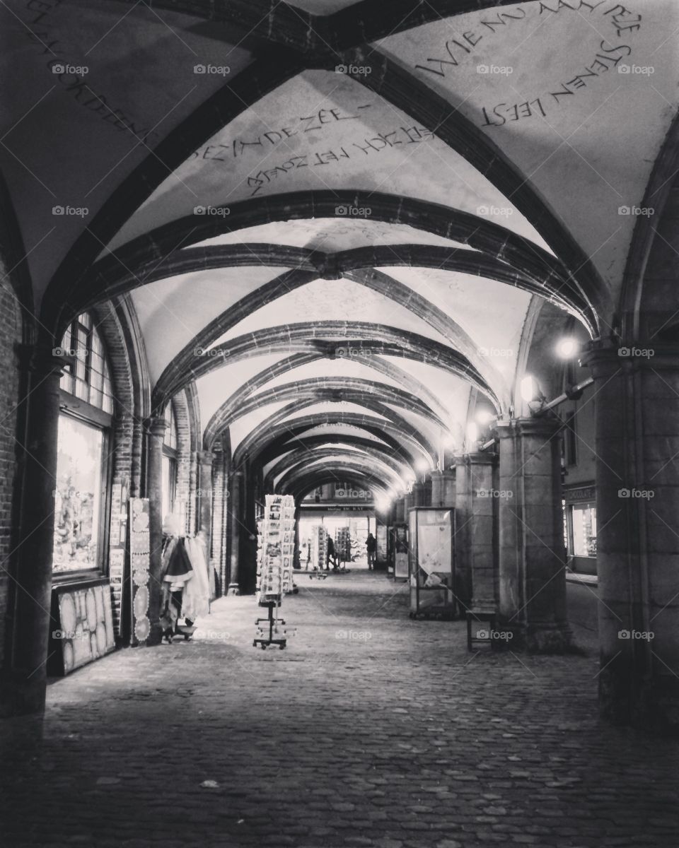 A walkway covered with old stone arches seems to be hold the last bit of activity before the historic town of Brugge, Belgium turns in for the night. 