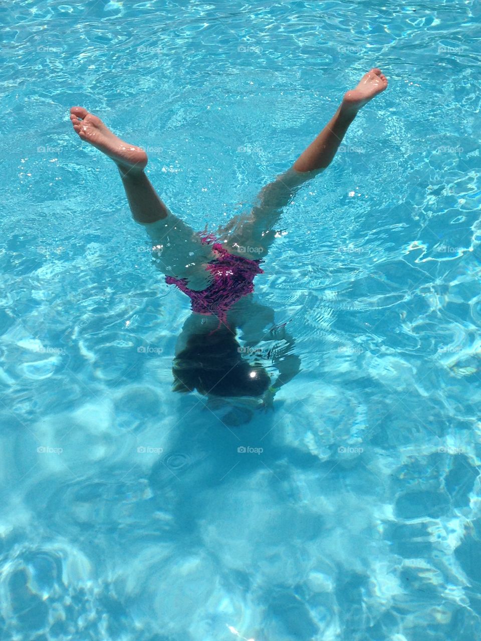 Pool tricks. Girl doing handstand underwater