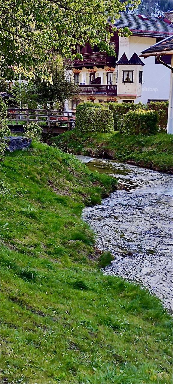 This picturesque landscape with a meandering brook between banks of lush dark green grass is in the vicinity of „Bayerischzell“, a small but very popular township near the Alps in „Bavaria“, Germany. 2024. Hypnotic Productions
