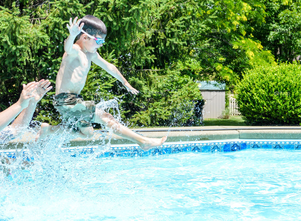 Young boy being thrown into a pool