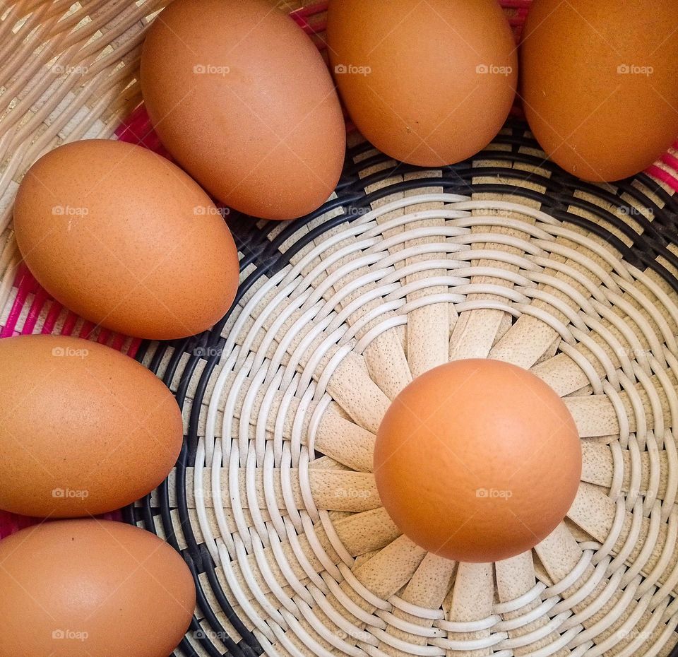 brown eggs inside a basket, arranged in a circle with an egg in the middle