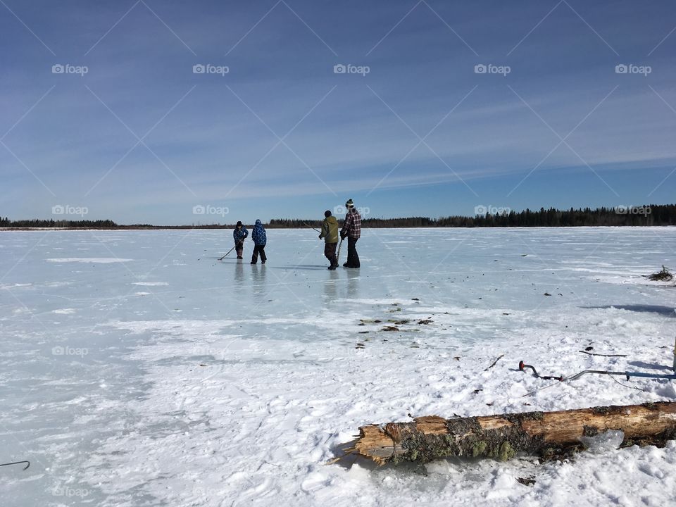 Kids plaing hockey on frozen lake.