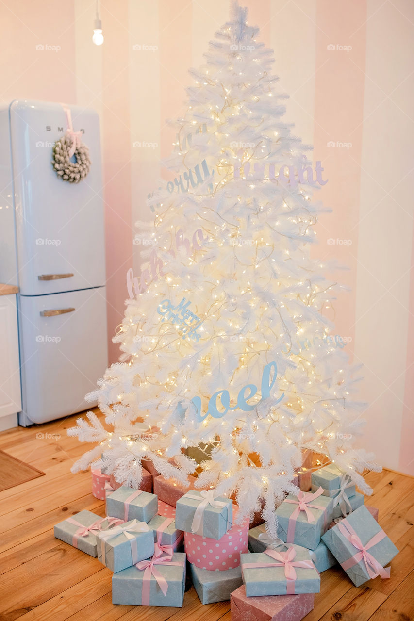 Festive winter cozy kitchen interior with garlands, decorations and gifts.  Christmas dinner at the decorated table.