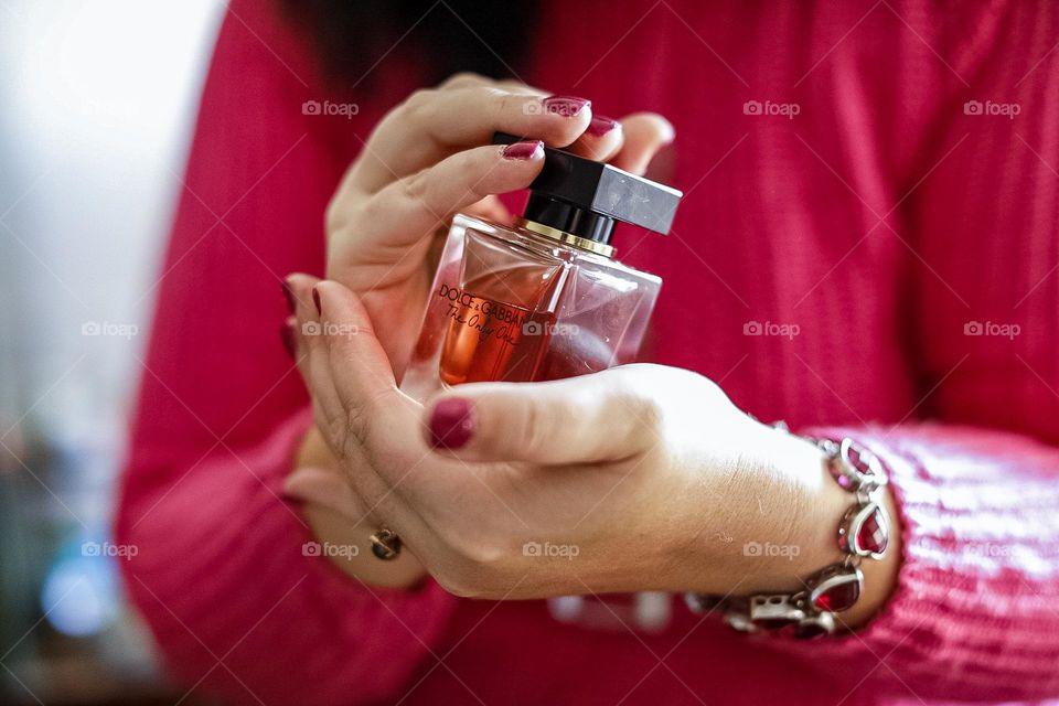 Wearing a ruby bracelet and holding a bottle of perfume