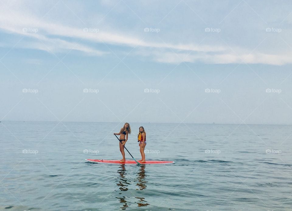 Sisters out on their paddle board in the summer