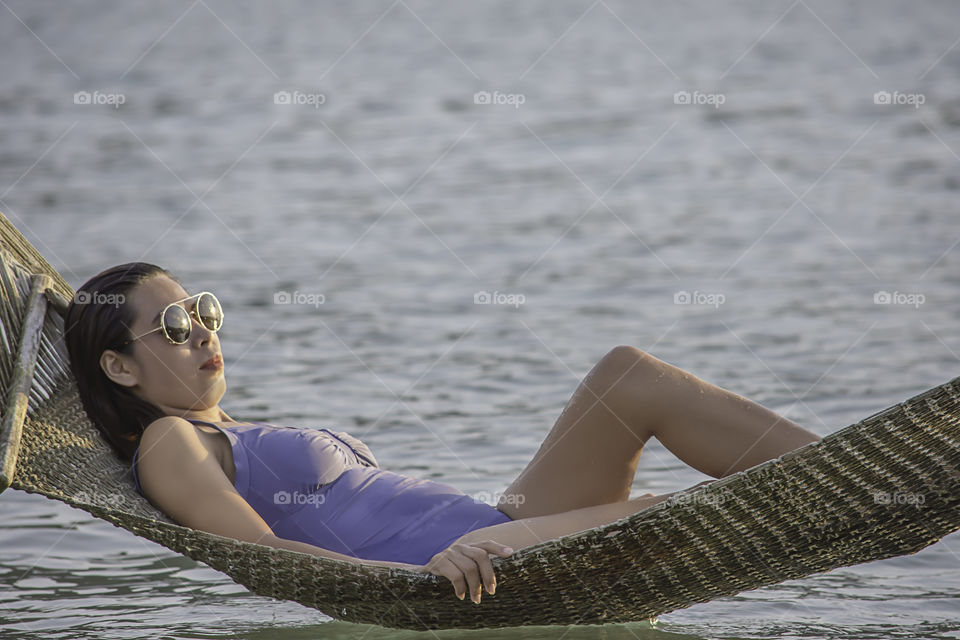 Portrait of Asian woman wearing a swimsuit on Hammock swing in sea.