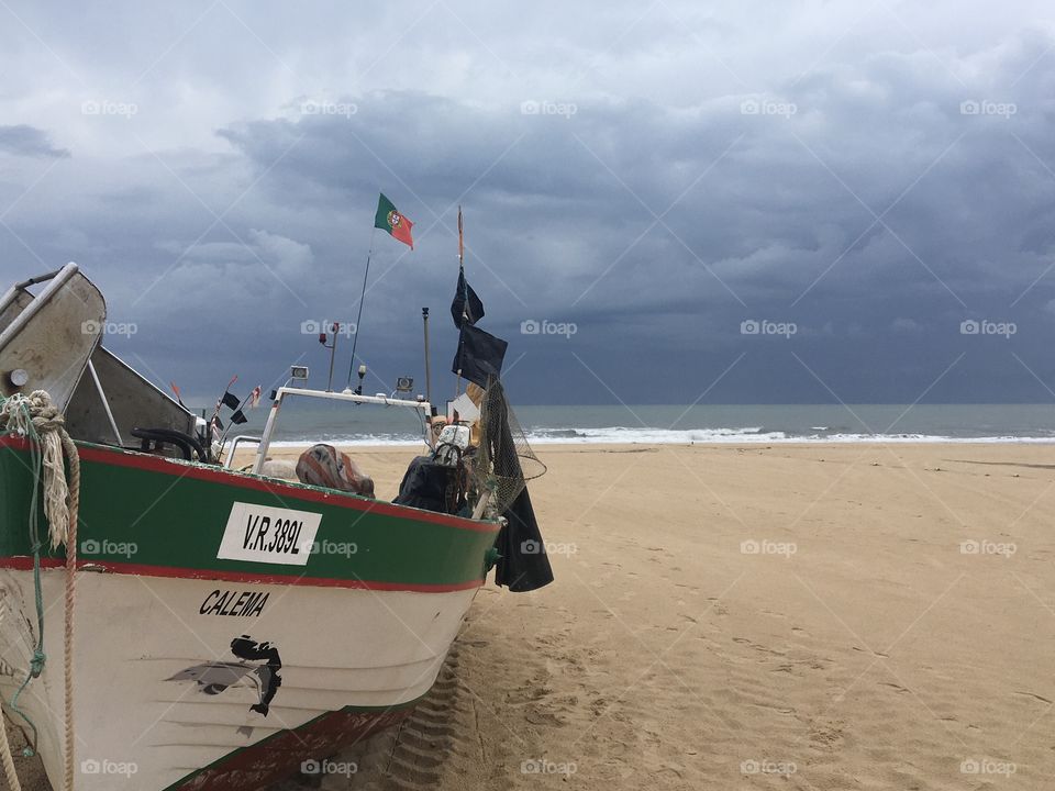 Fisherman’s boat on sandy beach with storm on sea