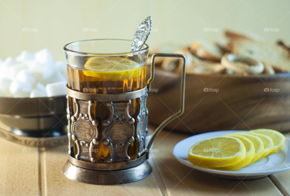 Tea in a glass in an old cup holder with drying and lemon