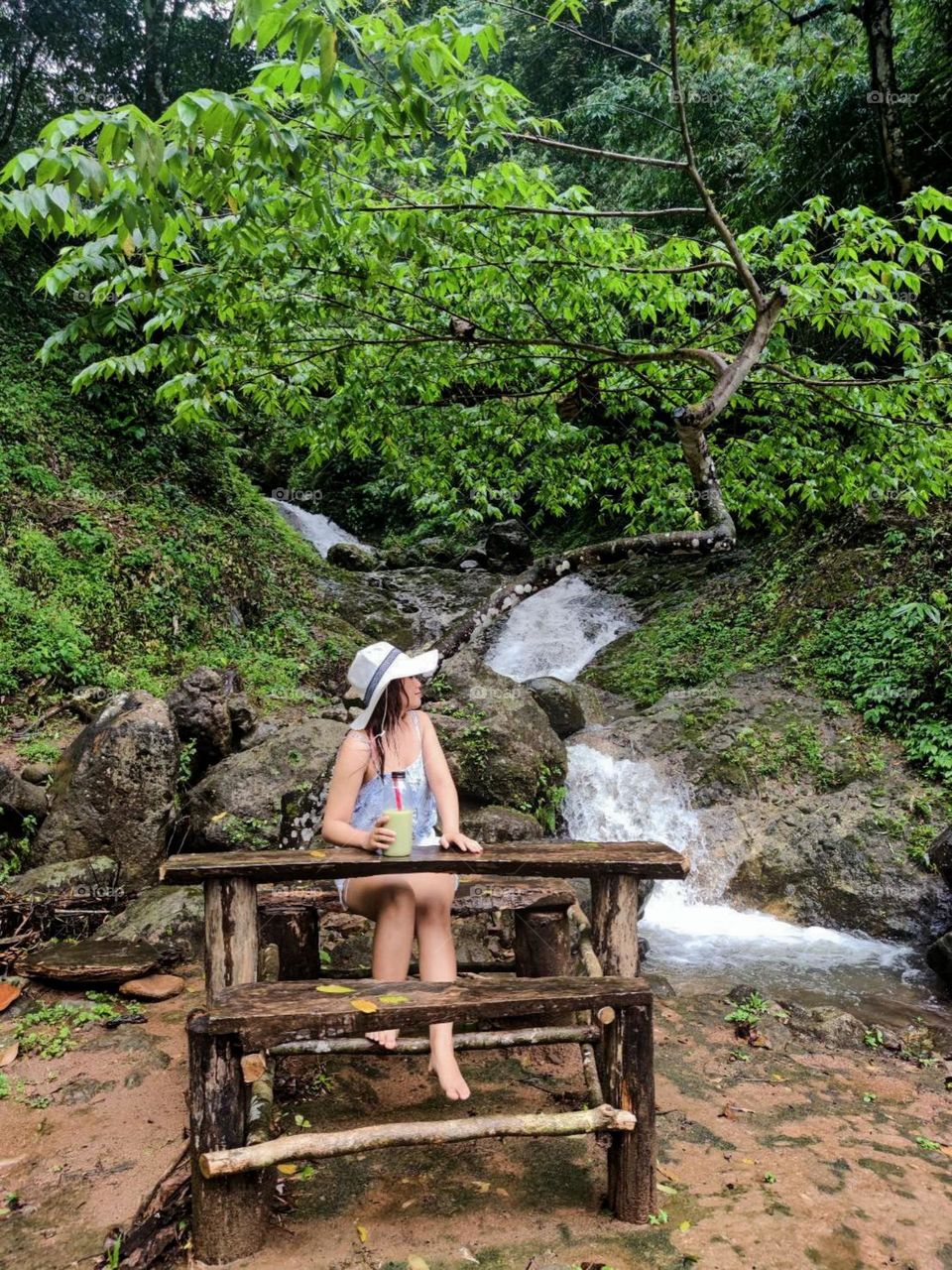 Portrait of woman sitting against waterfall