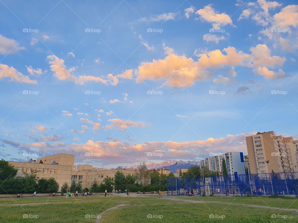 urban evening at school stadium in Almaty with mountains snd buildings