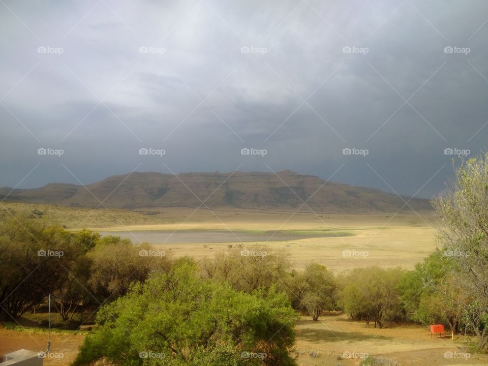 Black Mountain in central South Africa, during afternoon thunder storm. Low lying grassland and animal drinking hole.