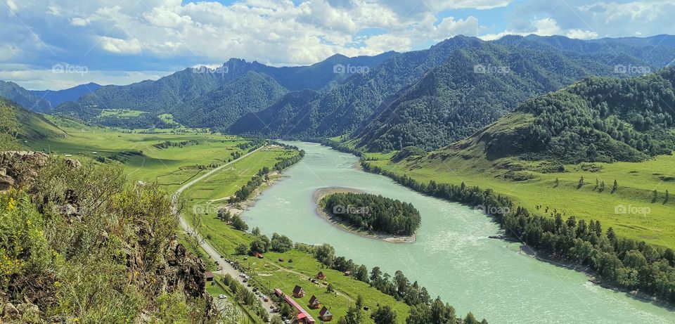 Beautiful view of the river with a small island and mountains in the distance on a sunny summer day