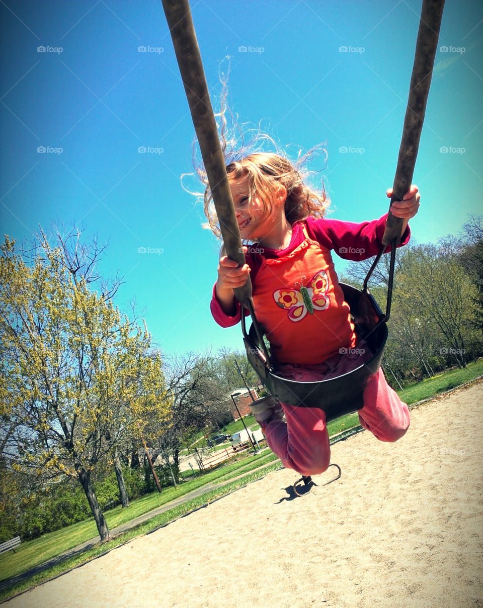 Adorable girl having fun on a swing on summer day