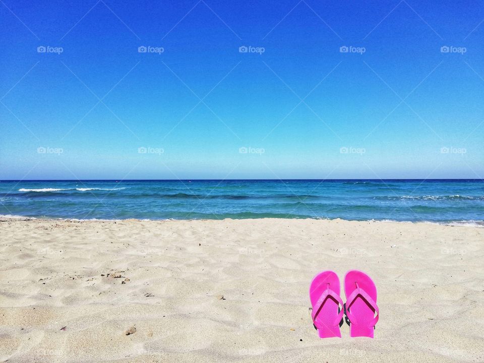 Flip flops in the sand and blue sea