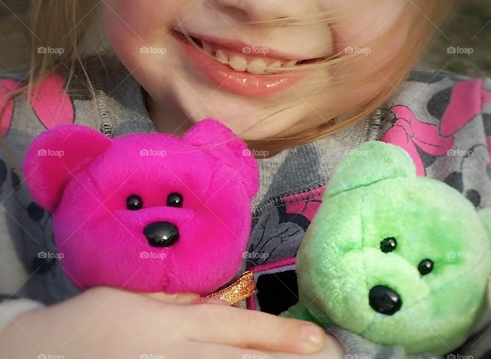 A young girl smiling hugging her beanie baby bears