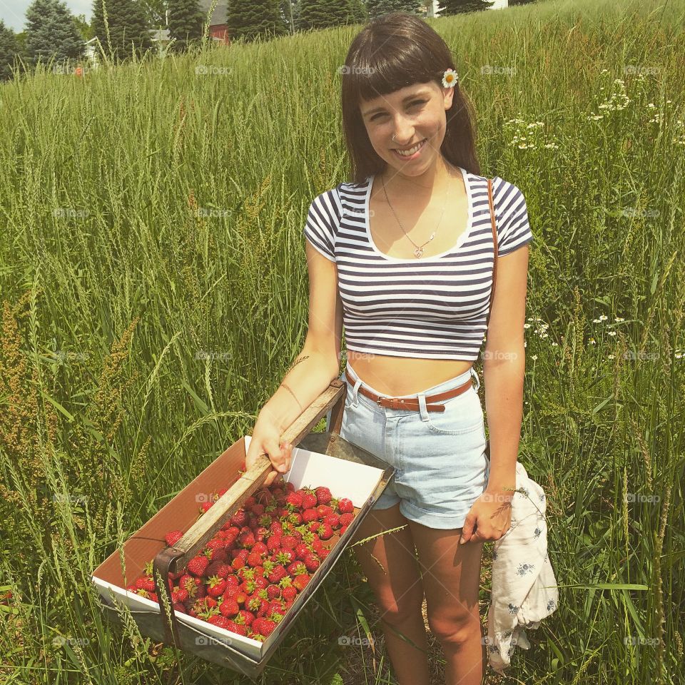 Front view of young smiling woman with strawberries in basket