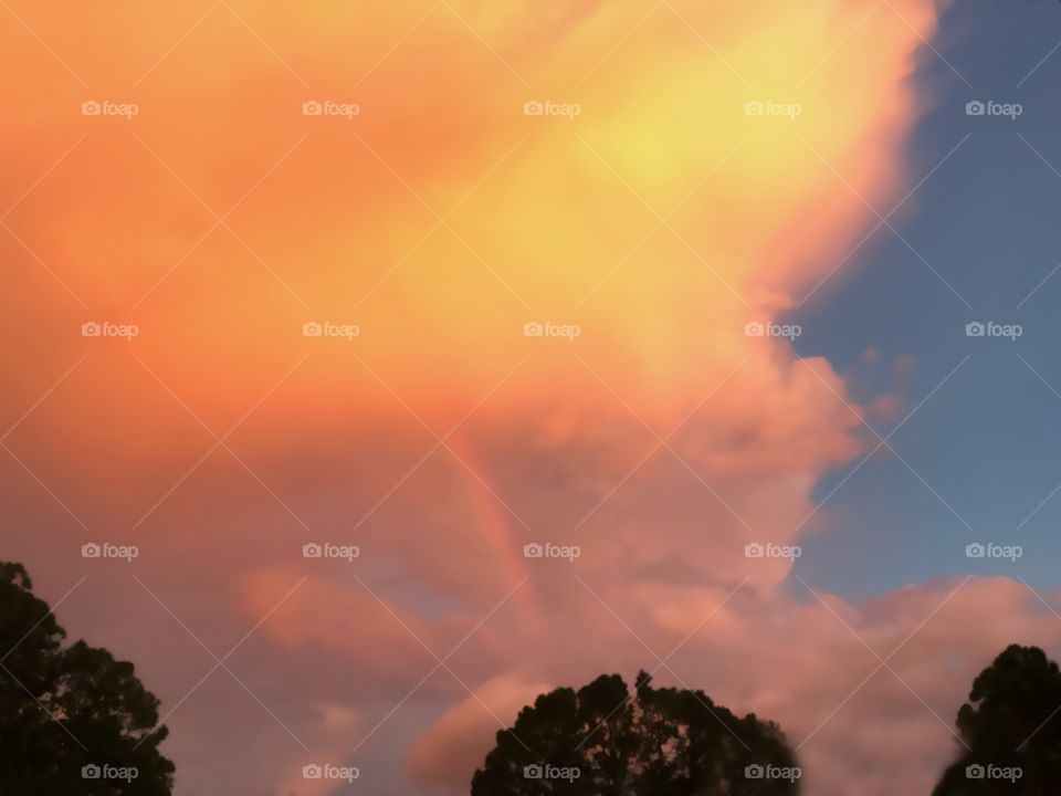 Unique towering golden sunset with a beautiful rainbow inside.