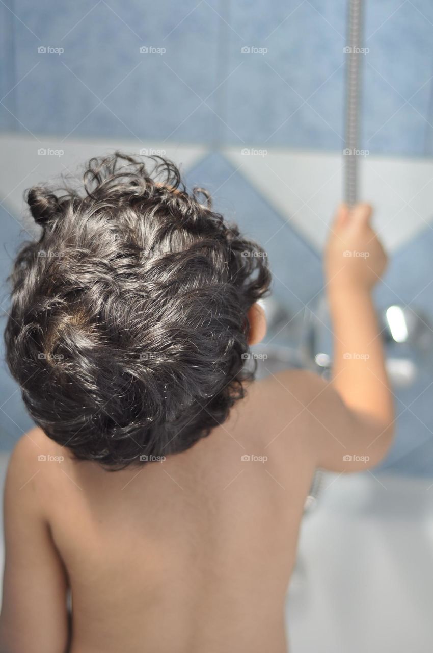 Infant boy taking shower in the bath tub