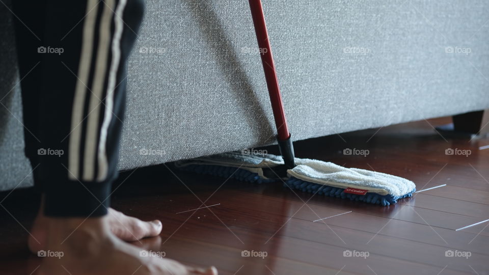 Mop sweeping dirt from under furniture.